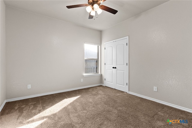 carpeted empty room featuring ceiling fan and baseboards