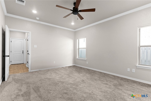 unfurnished room with light colored carpet, a ceiling fan, baseboards, visible vents, and ornamental molding