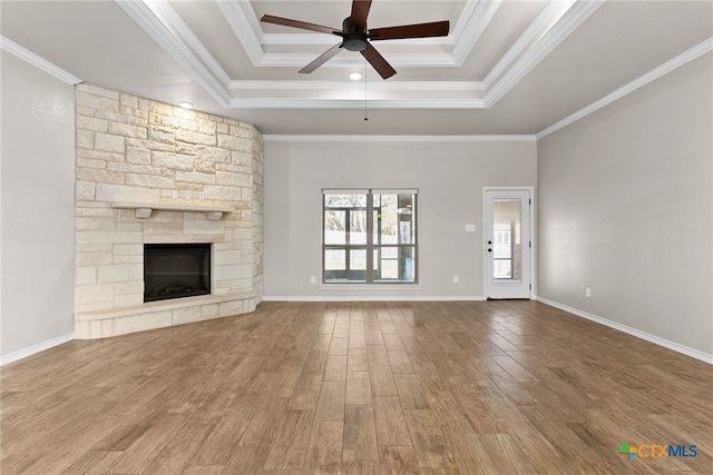 unfurnished living room featuring ornamental molding, wood finished floors, a fireplace, and a raised ceiling