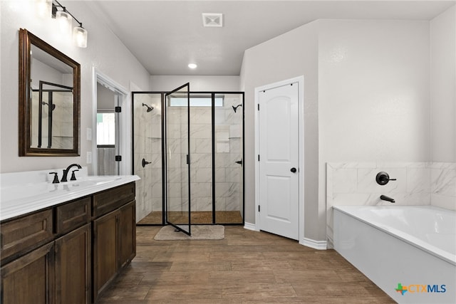 full bath featuring a stall shower, visible vents, wood finished floors, a garden tub, and vanity