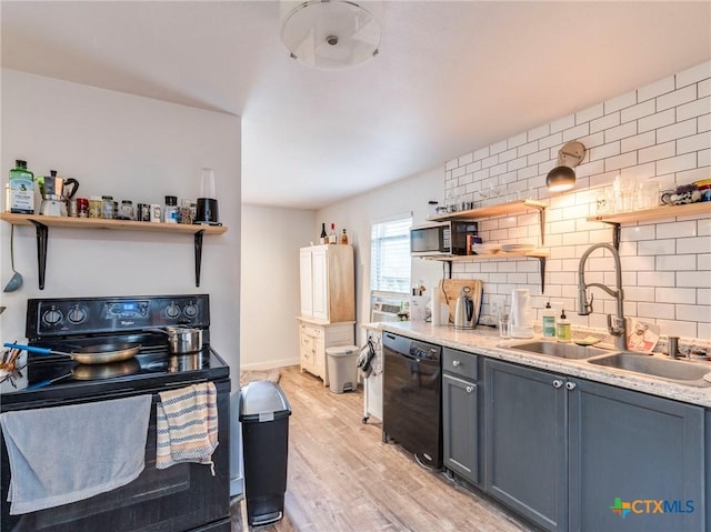 1000 Advance St, San Marcos, TX 78666 - kitchen featuring light wood-style floors, tasteful backsplash, open shelves, black appliances, and a sink