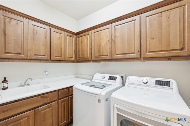 washroom with a sink, cabinet space, and washing machine and clothes dryer