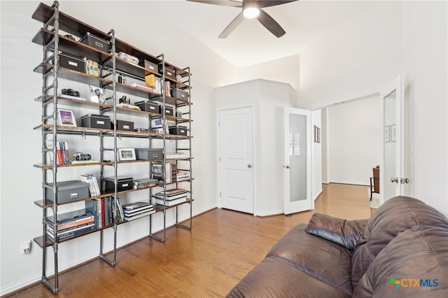 living area featuring baseboards, ceiling fan, and wood finished floors