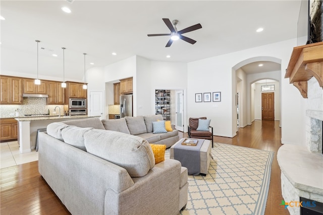 living area featuring light wood finished floors, recessed lighting, arched walkways, and ceiling fan