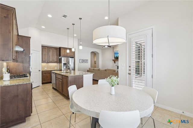 dining room with light tile patterned floors, visible vents, arched walkways, and recessed lighting