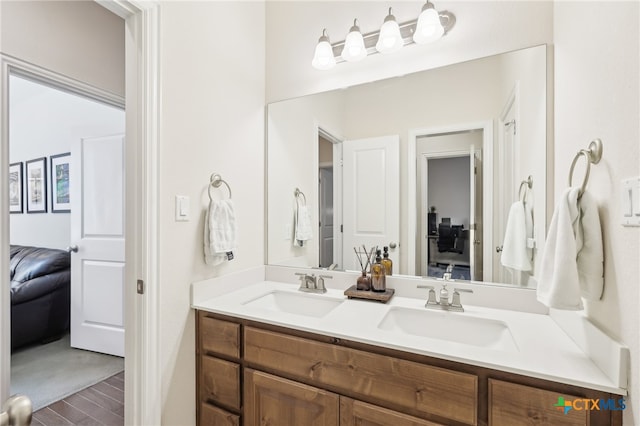 bathroom featuring double vanity, wood finished floors, ensuite bathroom, and a sink