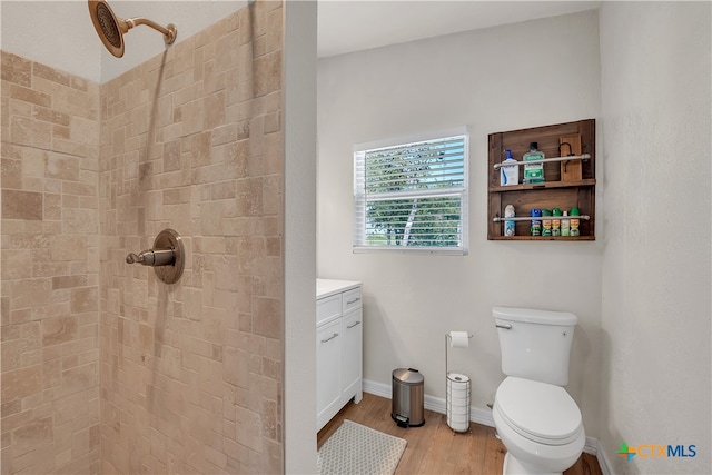 bathroom featuring hardwood / wood-style floors, vanity, toilet, and a tile shower