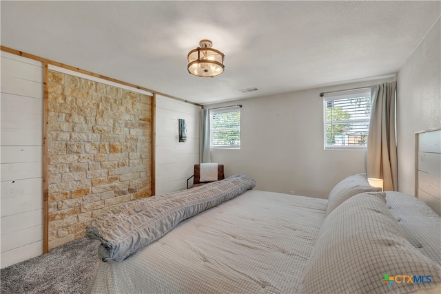 bedroom featuring wood walls and a textured ceiling