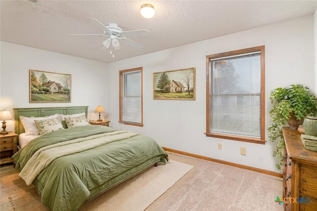 carpeted bedroom featuring a ceiling fan, a textured ceiling, and baseboards