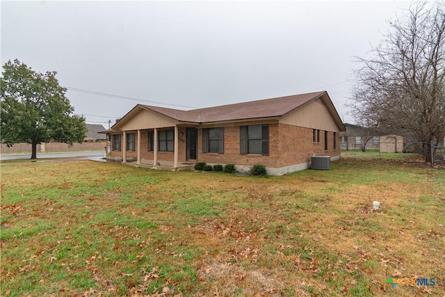 view of front of property with central AC, brick siding, a front lawn, and fence