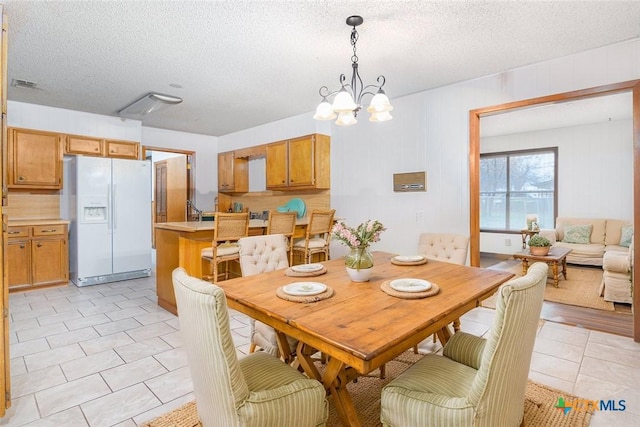 dining room with a textured ceiling, light tile patterned floors, a chandelier, and visible vents