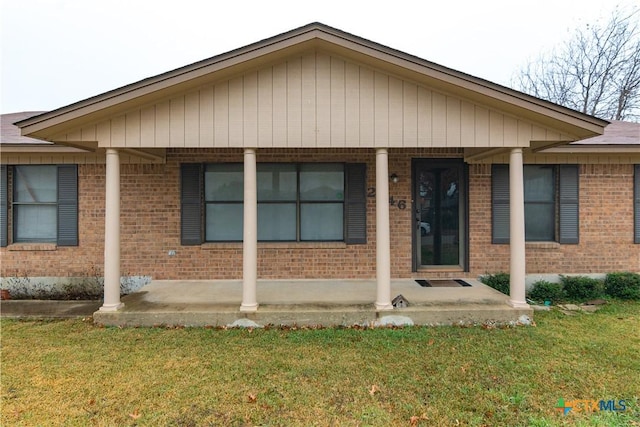 view of front of home with brick siding, a porch, and a front yard