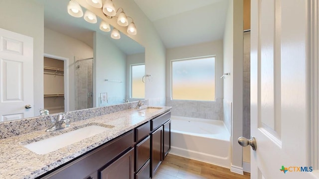 bathroom with hardwood / wood-style flooring, vanity, and a tub to relax in