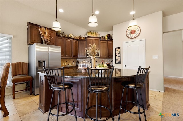 2194 Pioneer Pass, Seguin, TX 78155 - kitchen featuring stainless steel fridge with ice dispenser, decorative backsplash, dark stone counters, and an island with sink