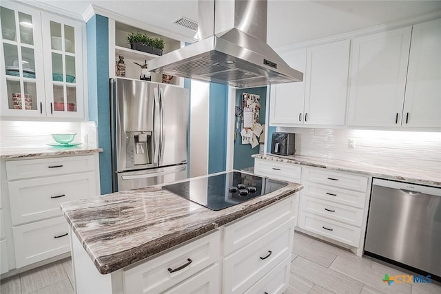 kitchen featuring island range hood, appliances with stainless steel finishes, light stone counters, and glass insert cabinets