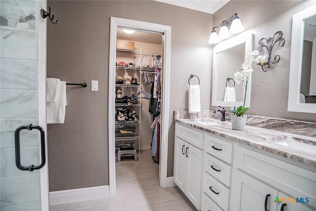full bath with a textured wall, a stall shower, a walk in closet, and vanity