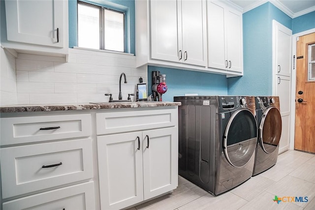 laundry room featuring ornamental molding, a sink, cabinet space, and separate washer and dryer