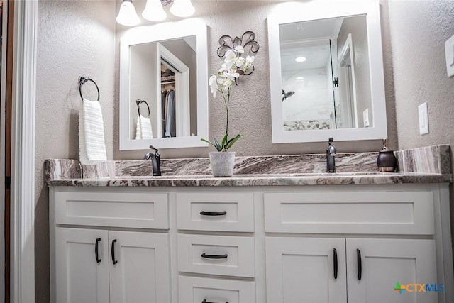bathroom with a sink, double vanity, and a textured wall