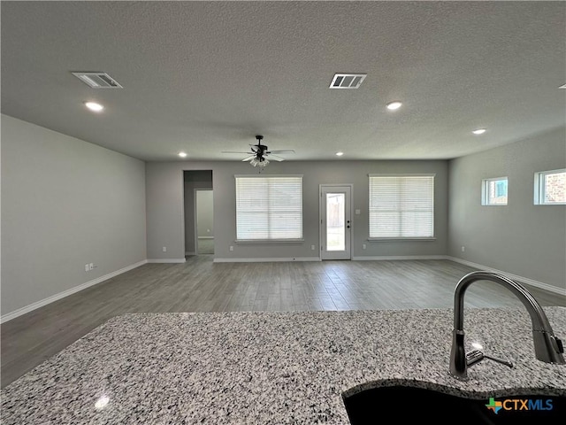 living room featuring sink, wood-type flooring, a textured ceiling, and ceiling fan