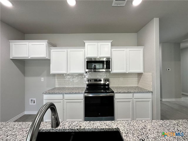 kitchen featuring stainless steel appliances, white cabinets, and light stone countertops