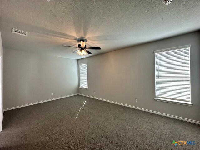 spare room featuring ceiling fan, a textured ceiling, and dark colored carpet