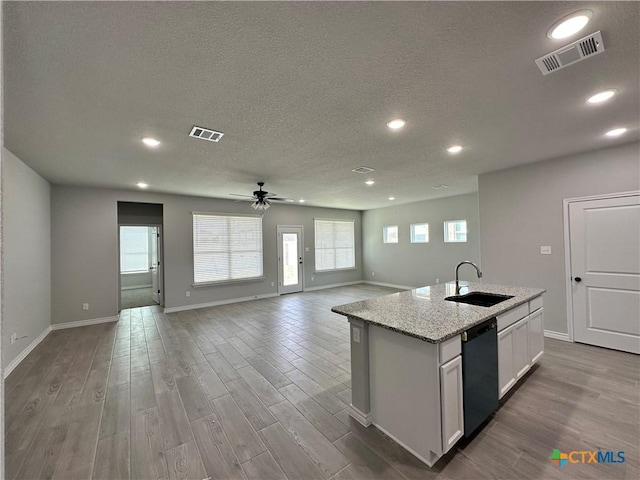 kitchen with sink, white cabinetry, dishwasher, light stone counters, and ceiling fan