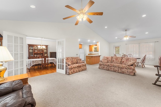 living room featuring carpet, ceiling fan with notable chandelier, high vaulted ceiling, and french doors