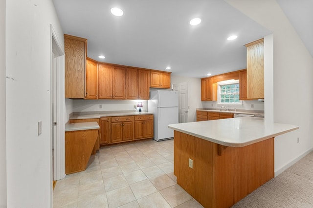 kitchen featuring a kitchen breakfast bar, white refrigerator, sink, light tile patterned floors, and kitchen peninsula