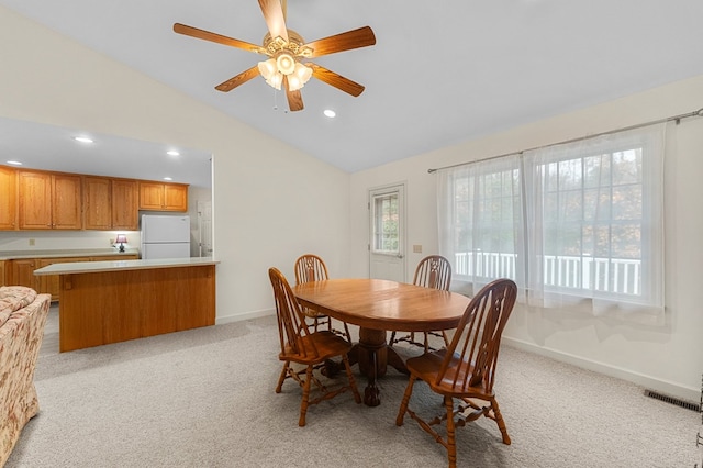 dining room with ceiling fan, light carpet, and vaulted ceiling