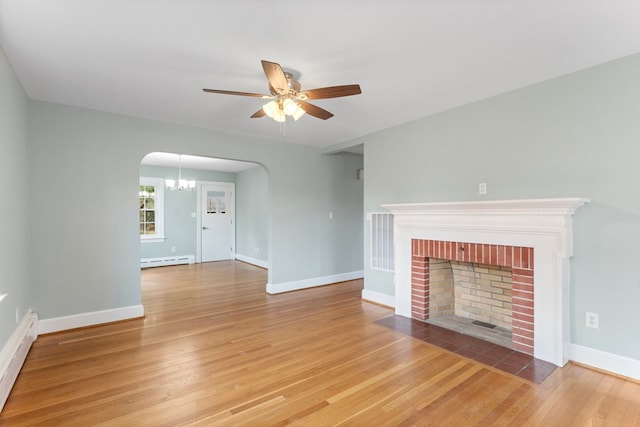 unfurnished living room with hardwood / wood-style floors, a fireplace, a baseboard radiator, and ceiling fan with notable chandelier