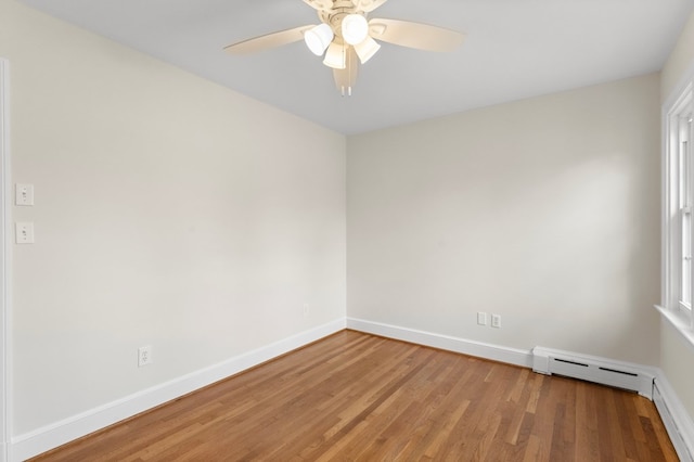 spare room with ceiling fan, a baseboard heating unit, and hardwood / wood-style flooring