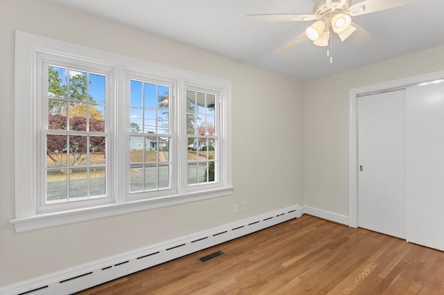 unfurnished bedroom featuring ceiling fan, a closet, multiple windows, and a baseboard radiator