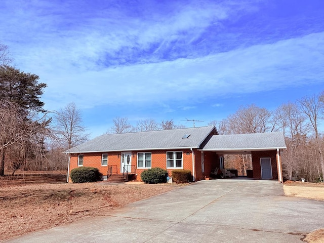 single story home with a carport, brick siding, and driveway