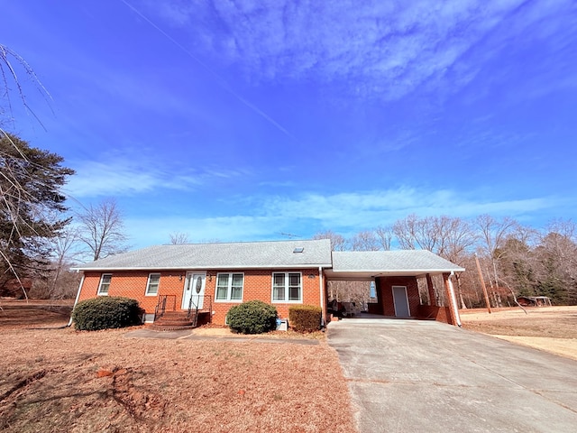 ranch-style home with a carport, concrete driveway, and brick siding