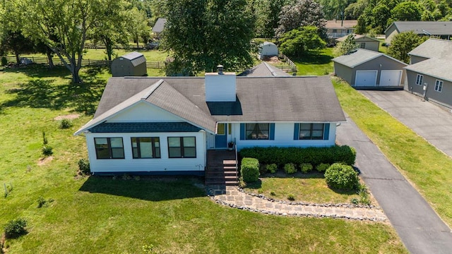 view of front of home featuring a garage, an outdoor structure, and a front yard