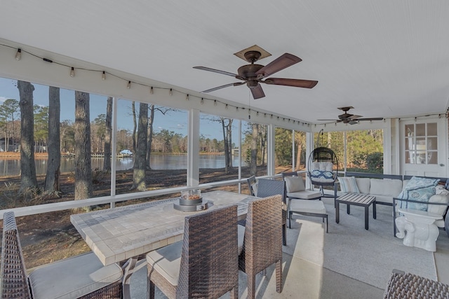 sunroom / solarium with a water view, ceiling fan, and a healthy amount of sunlight