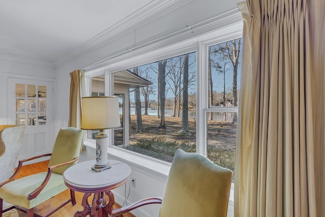 living area with crown molding, a water view, and hardwood / wood-style flooring