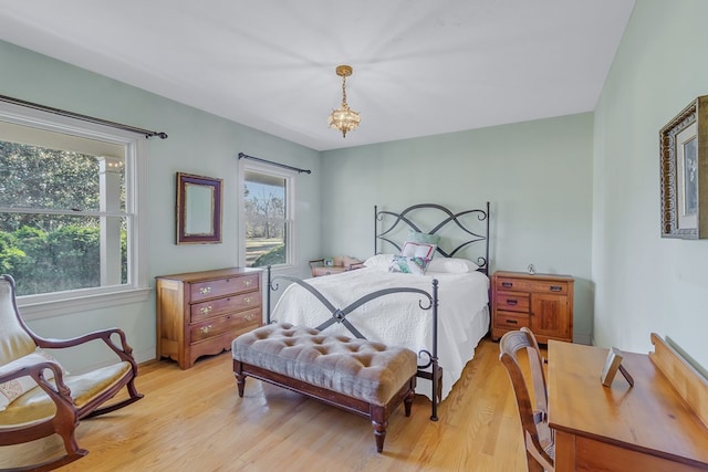 bedroom with a chandelier and light wood-type flooring