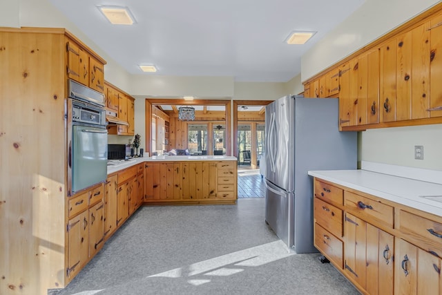 kitchen with wall oven, stainless steel fridge, and kitchen peninsula