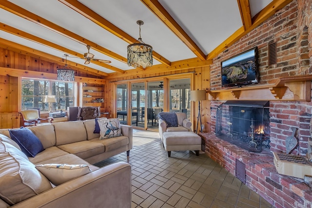 living room with wooden walls, ceiling fan, lofted ceiling with beams, and a brick fireplace