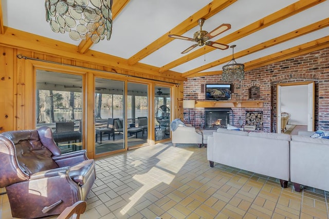 living room featuring vaulted ceiling with beams, ceiling fan, and a brick fireplace