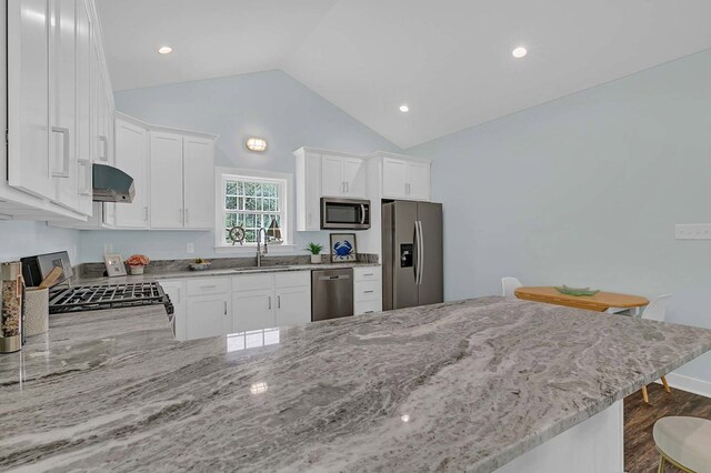 250 Pocahontas Ave, Deltaville, VA 23043 - kitchen with appliances with stainless steel finishes, dark wood-type flooring, light stone countertops, range hood, and lofted ceiling