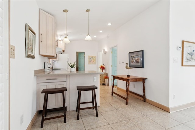 kitchen with light countertops, a kitchen bar, light tile patterned floors, a peninsula, and hanging light fixtures