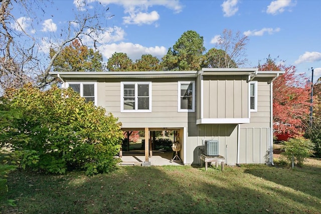 rear view of house featuring a lawn, cooling unit, and board and batten siding