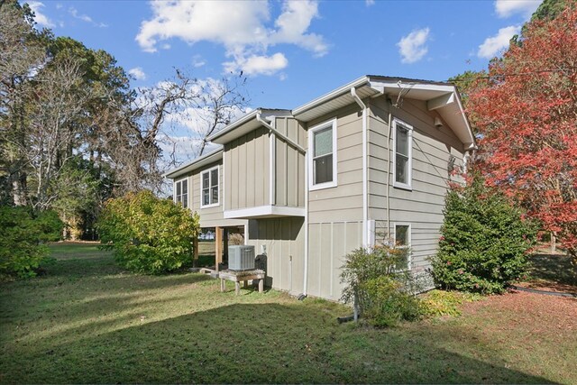 view of side of property featuring a yard, board and batten siding, and central AC