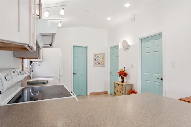 kitchen featuring white appliances, recessed lighting, track lighting, and vaulted ceiling