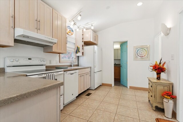 kitchen with white appliances, light tile patterned floors, a sink, vaulted ceiling, and under cabinet range hood