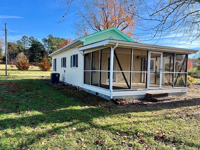 view of side of home featuring a sunroom, central AC unit, and a lawn