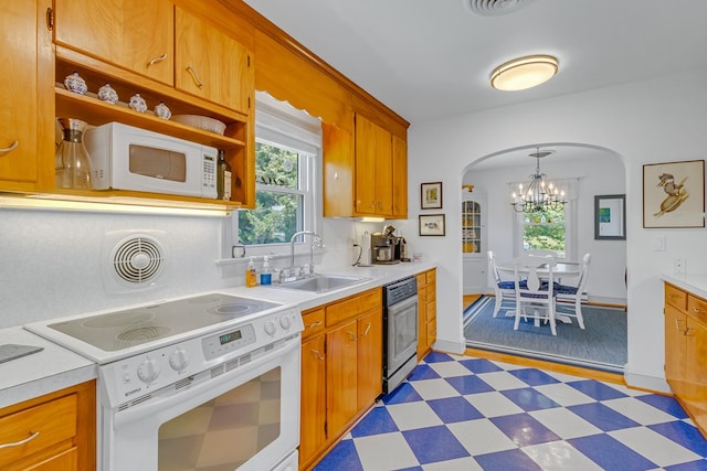 131 Henry Creek Ln, Kilmarnock, VA 22482 - kitchen featuring white appliances, a sink, arched walkways, light flooring, and a chandelier