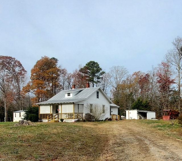 view of front facade featuring a front lawn, a chimney, and an outdoor structure